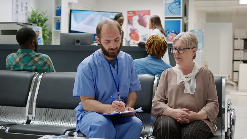 Medical assistant consulting old patient in waiting room lobby