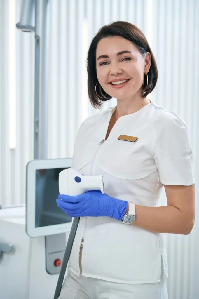 Woman physiotherapist holds an applicator of shock wave therapy apparatus